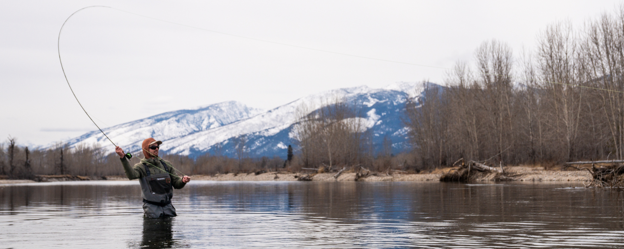 a man stands in a river while fly fishing