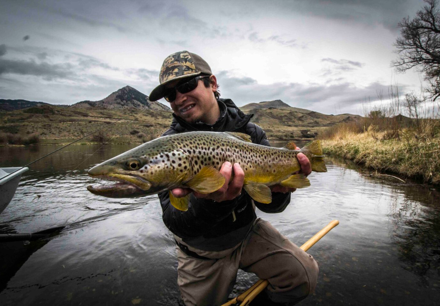 fly fisherman holds a large brown trout caught on the Missouri River near Craig, Montana