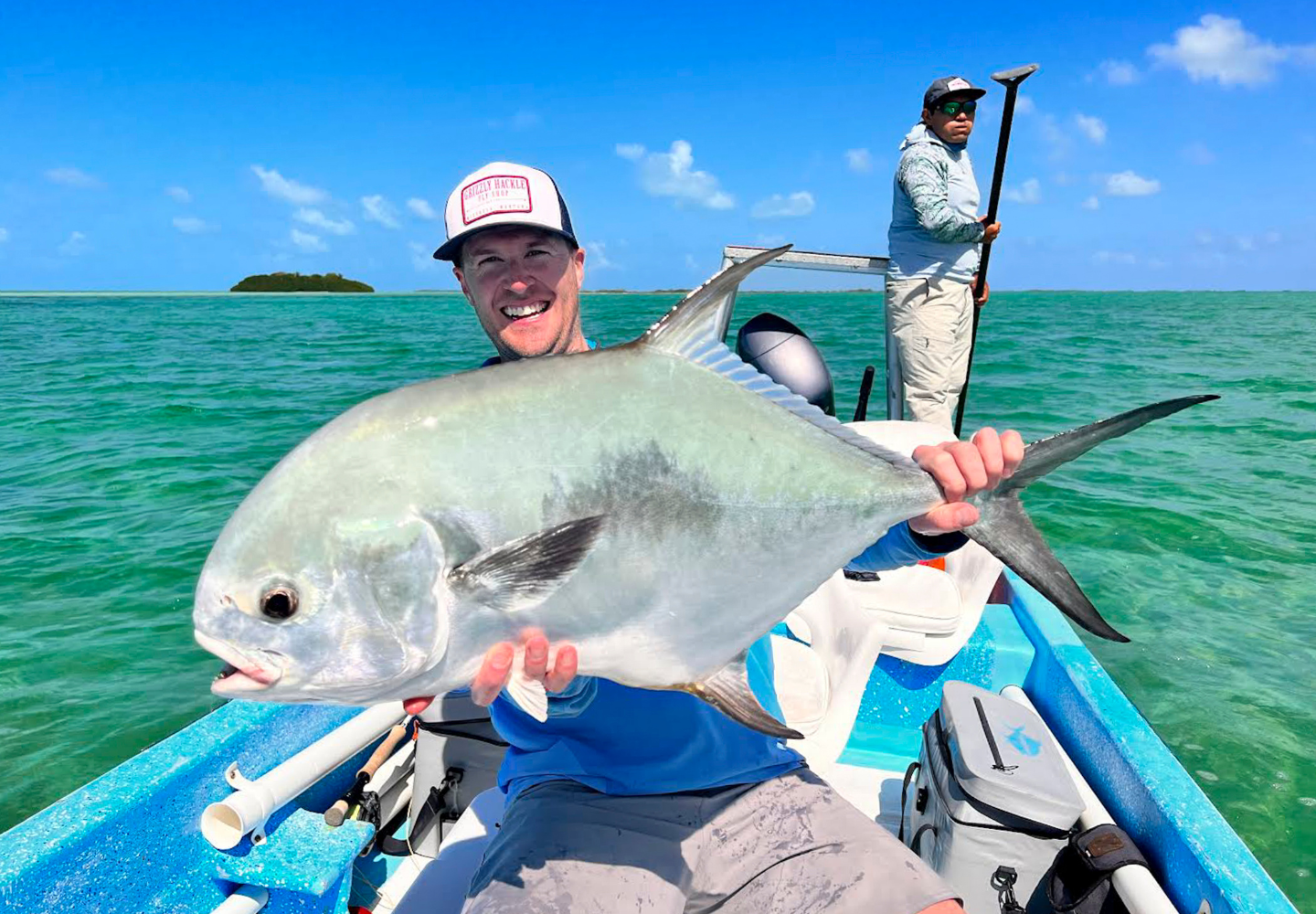 man holds permit above panga while fly fishing in Belize