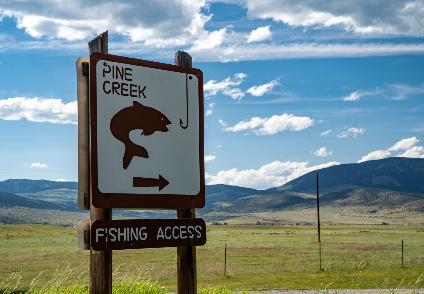 a fishing access sign on the yellowstone river in montana with green mountains in the background